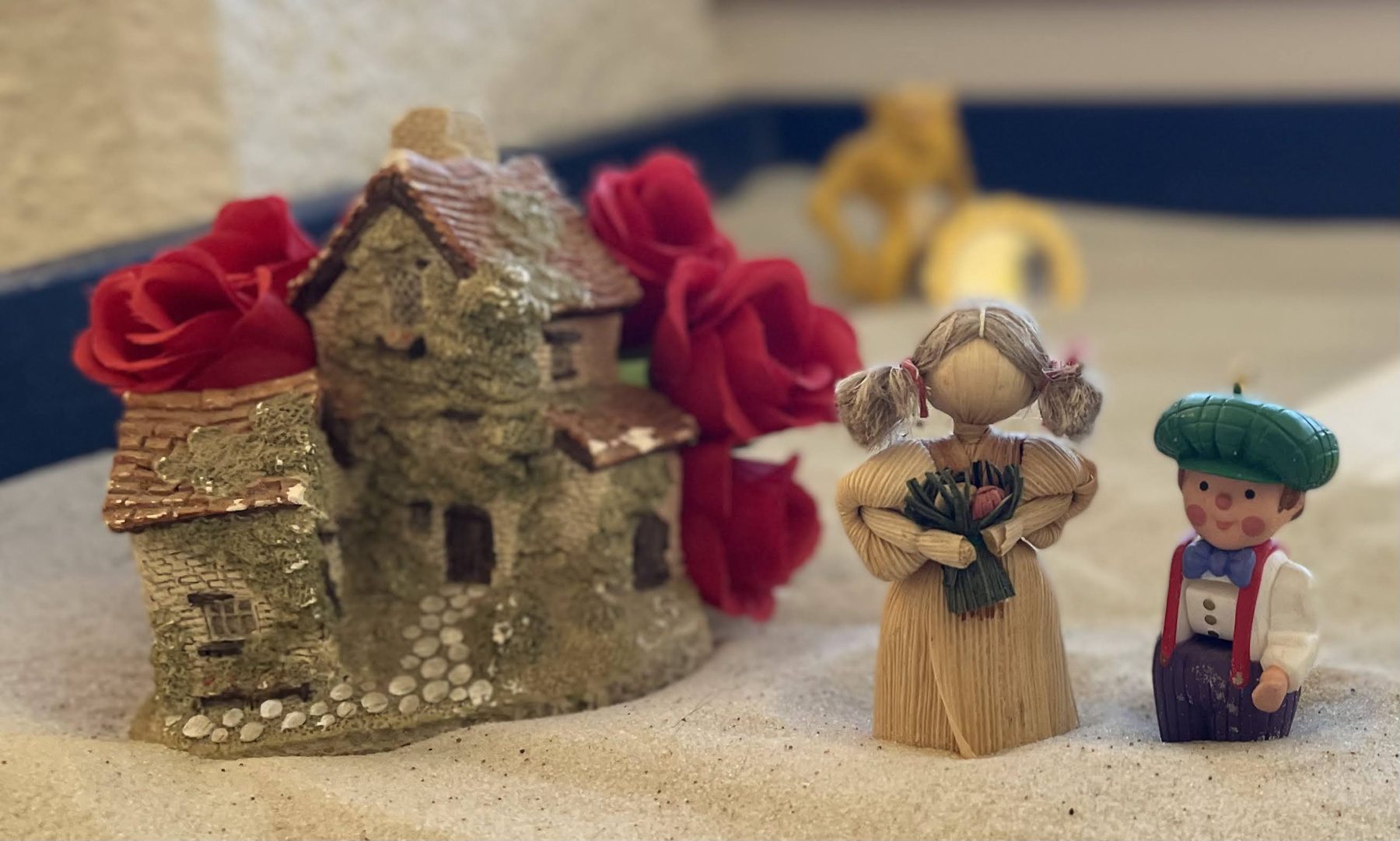 A sand tray with miniature figures arranged in the sand, used in Sandplay Therapy